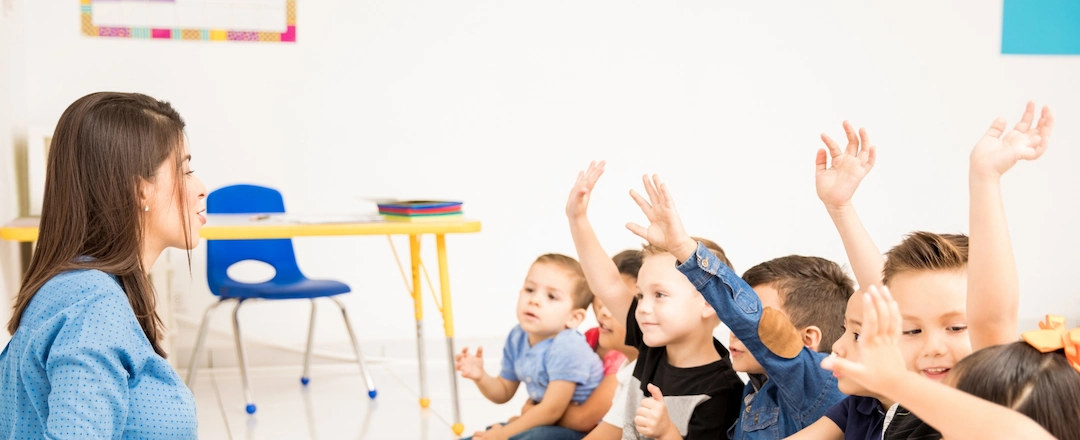Children Raising Hand to Teacher in Daycare Class