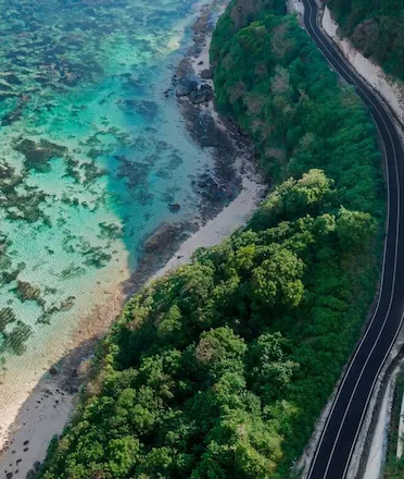 Aerial view of toll road beside crystal blue sea and beach Bali