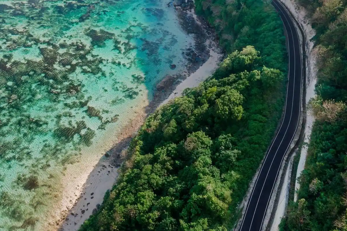 Aerial view of toll road beside crystal blue sea and beach Bali