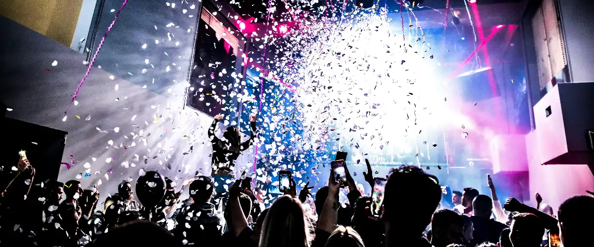 Crowd celebrating at a nightclub during New Year’s Eve as confetti rains down