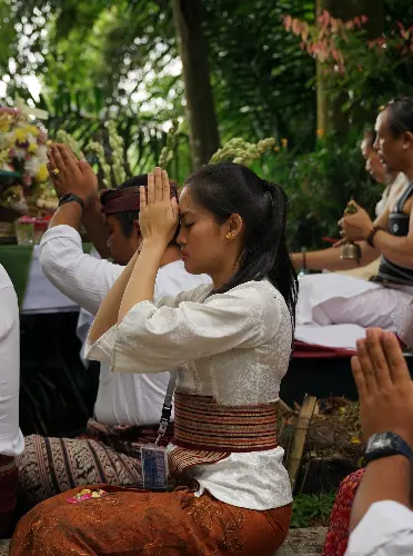 People sitting outdoors in prayer during a ceremonial ritual.