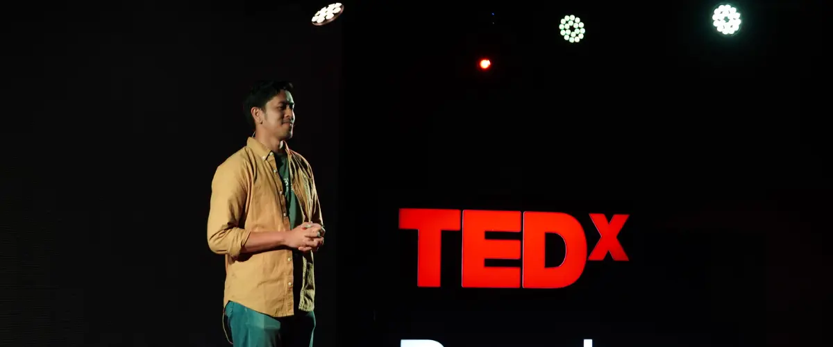 A speaker stands on the TEDxBandung stage