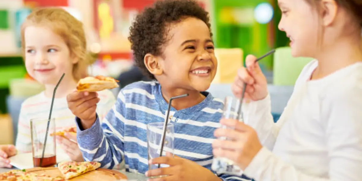 Children laughing and eating pizza at a kid-friendly restaurant.