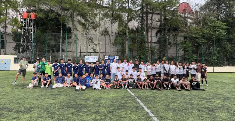 Students posing on a football field at a BIS charity tournament