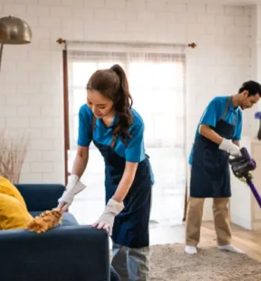 Two professional cleaners tidying a living room
