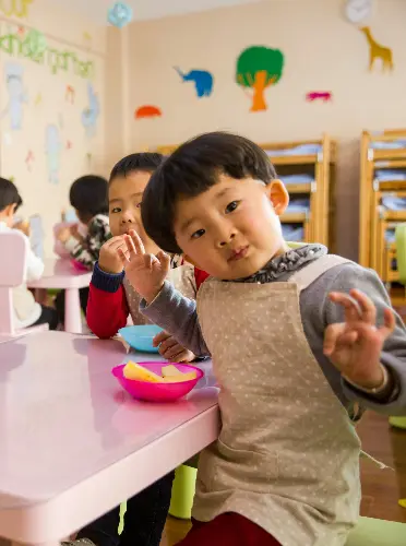 Children enjoying snack time together in a colorful preschool classroom.