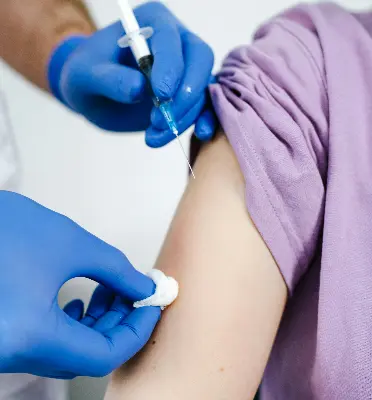 A healthcare worker administering a vaccine injection to a patient’s upper arm.