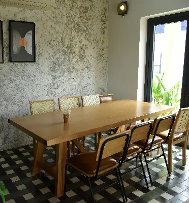 Minimalist private room with wooden table, mixed seating, and natural lighting at a cafe