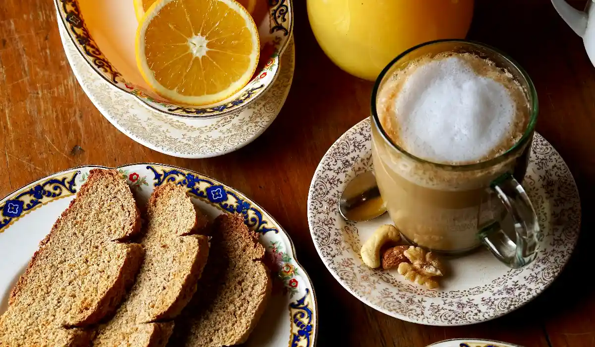 Breakfast spread with toast, jam, coffee, and fresh orange juice on a wooden table.