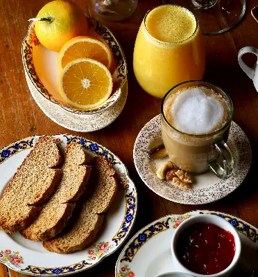 Breakfast spread with toast, jam, coffee, and fresh orange juice on a wooden table.