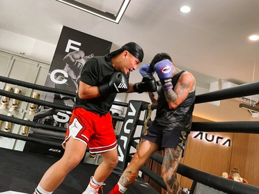 Boxing training session inside Aura Combat Studio, with two athletes sparring in the ring.