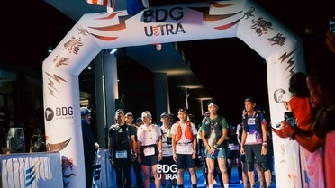 Runners gather at the BDG100 Ultra Trail Run starting arch in Bandung before the race begins.