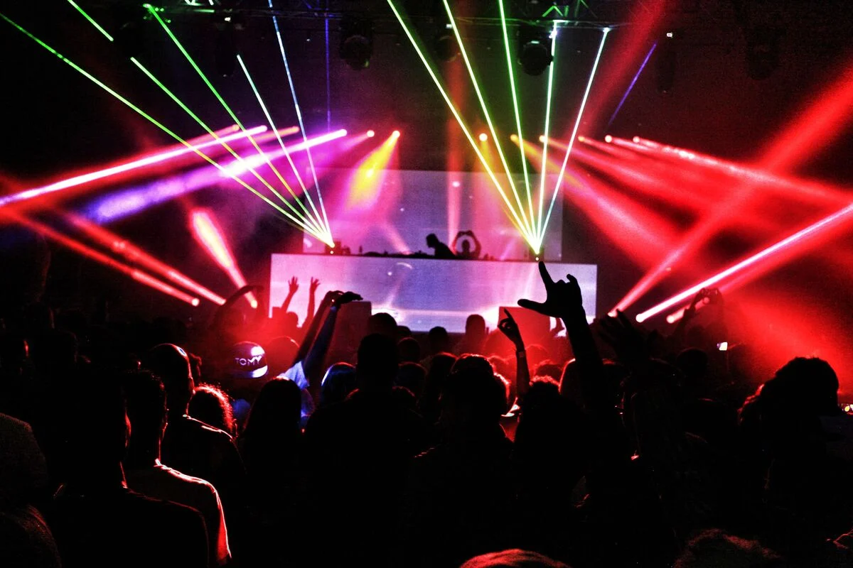 Energetic nightclub scene with laser lights and a lively crowd dancing to EDM music