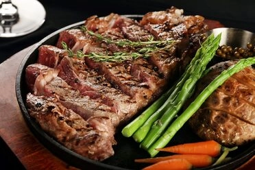 Delicious grilled steak with vegetables on a black slate plate