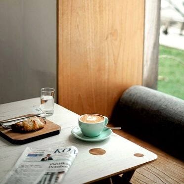 A cozy morning scene with cappuccino, croissant, and newspaper 
