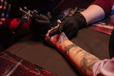 A tattoo artist working on a client’s arm