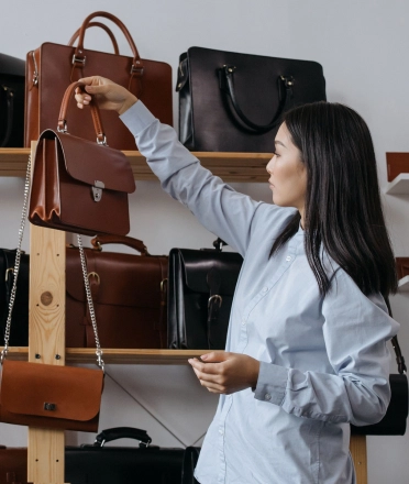 Woman_checking_leather_handbags_in_a_showroom.webp